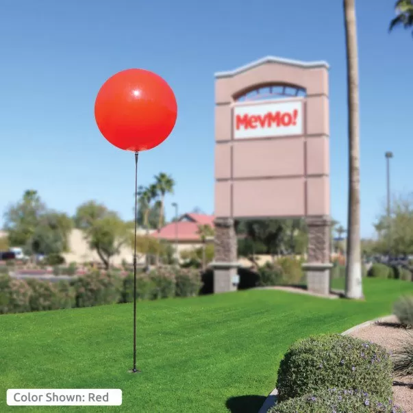 Red 30-inch MegaBalloon on a ground-mounted pole beside a business
