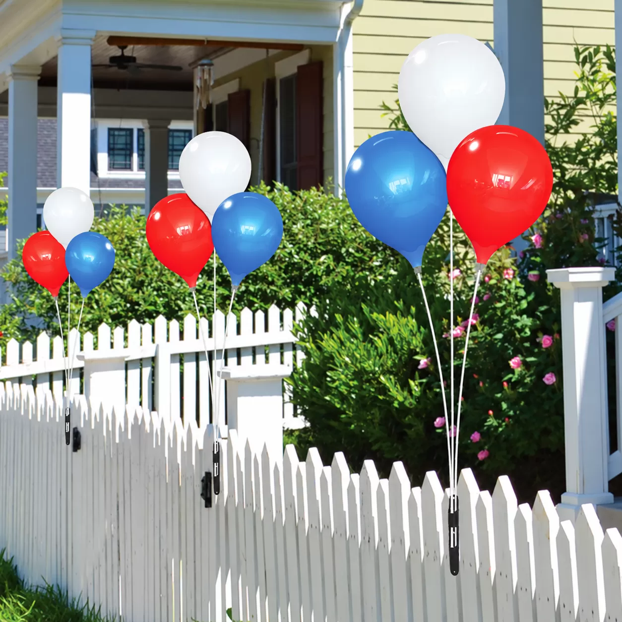 Red, white and blue PermaShine three-balloon displays mounted to a white fence