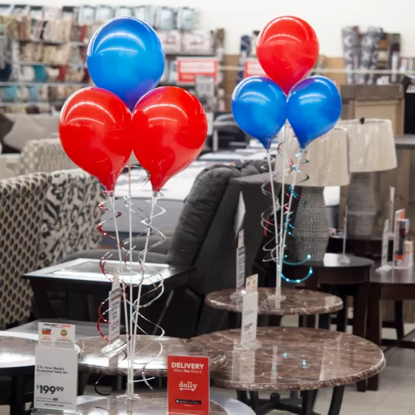 Red and blue PermaShine three-balloon bouquets on retail display tables