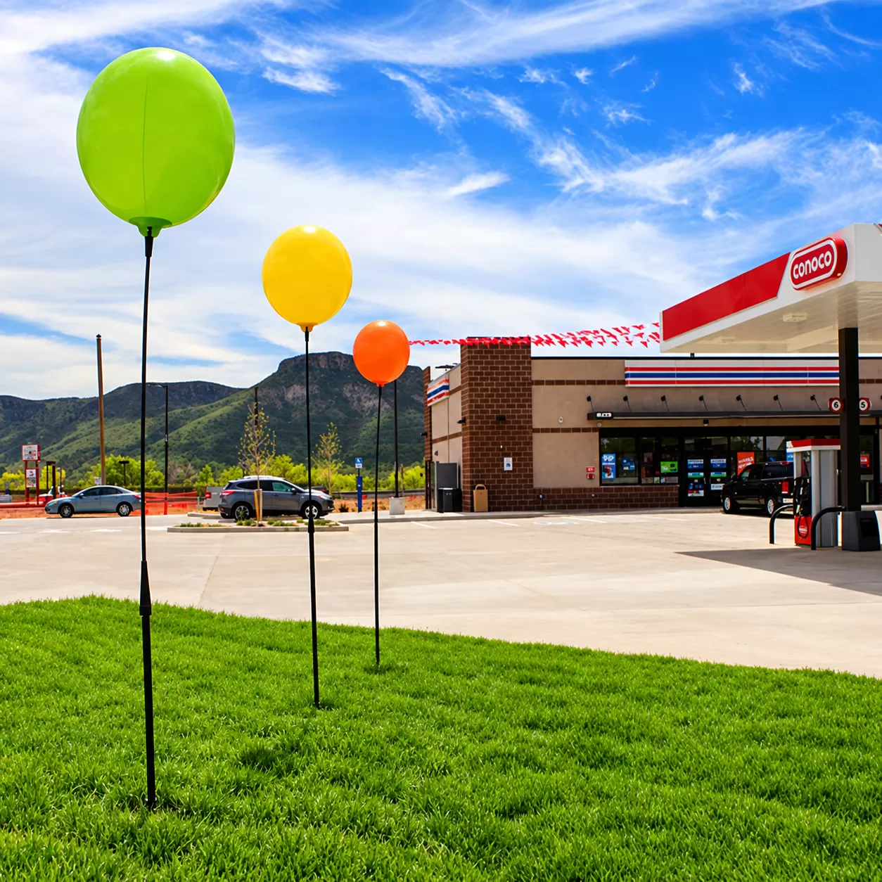 Lime, yellow and orange DuraBalloon short-pole displays beside a storefront