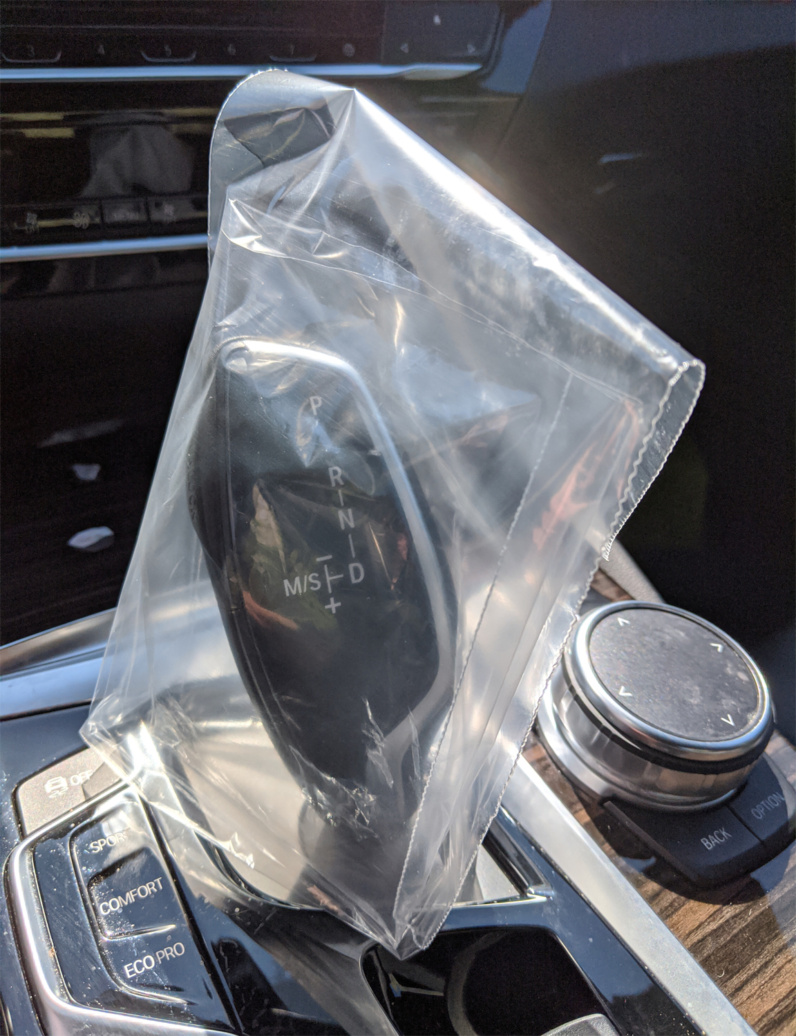 Clear disposable plastic gear shift cover protecting a vehicle gearshift