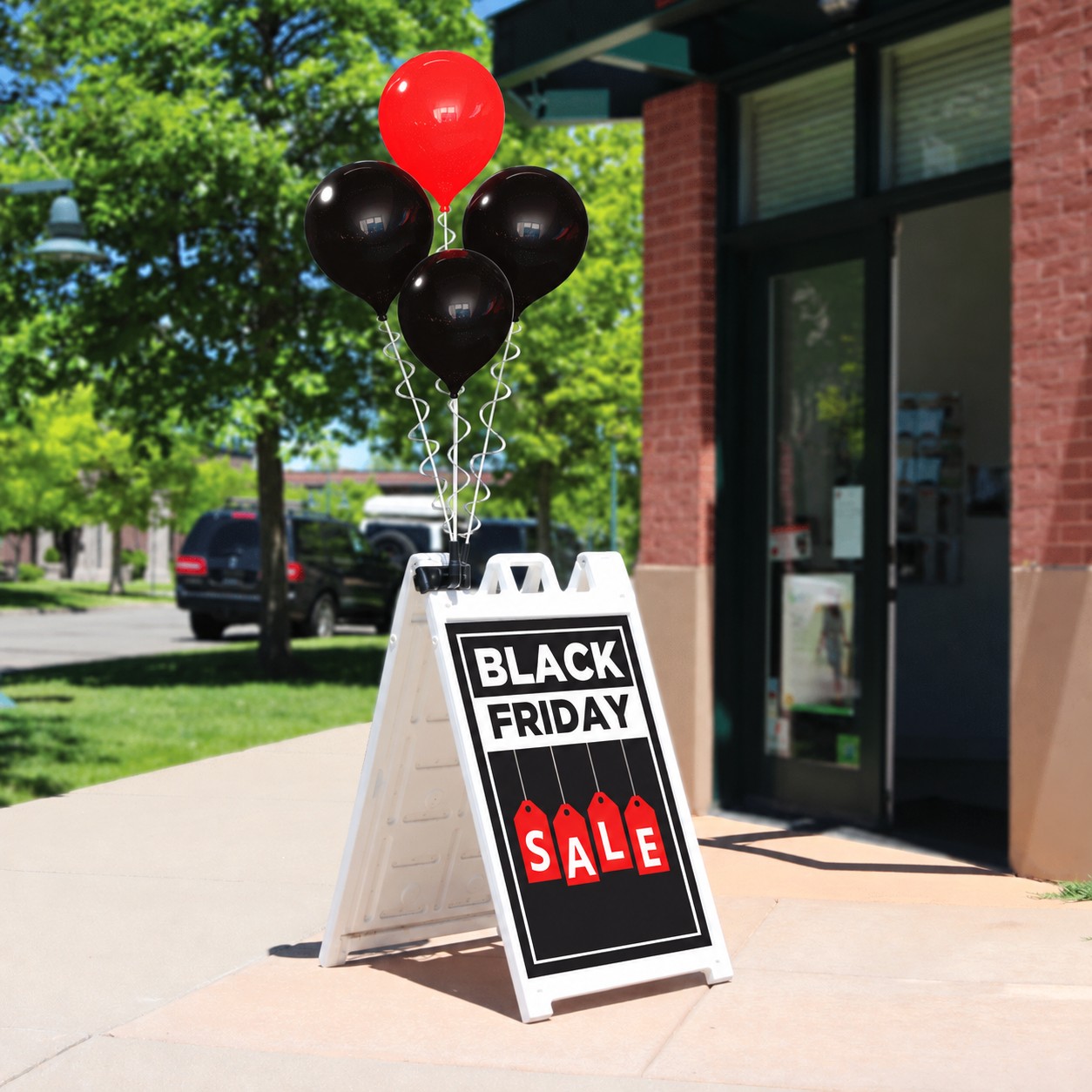 Four PermaShine balloons, one red and three black, above a white Signicade with Black Friday SALE tag artwork
