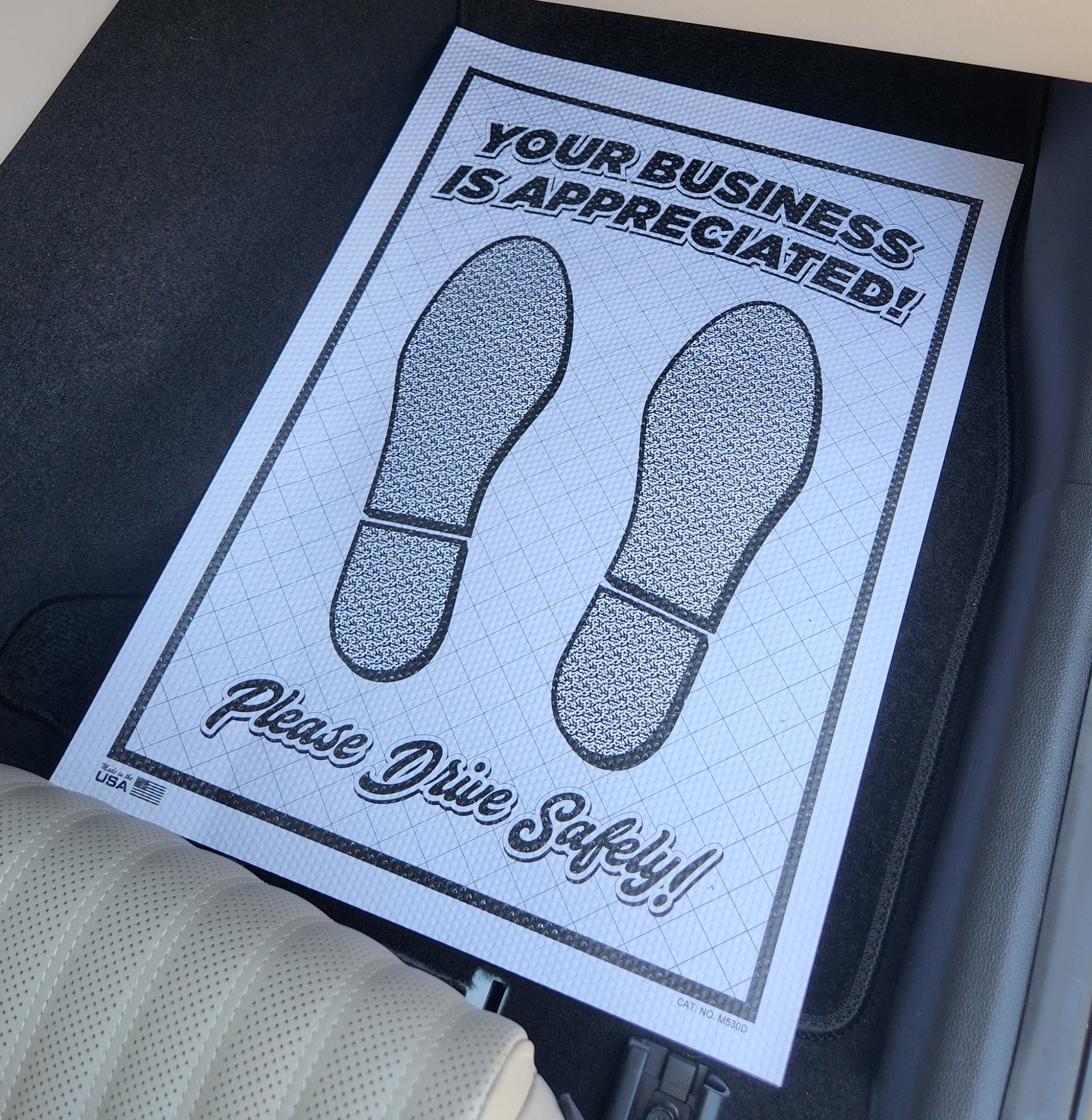 White double poly-coated paper floor mat with black footprints and thank-you message